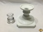 Lote de 2 castiçais, sendo um em vidro incolor e um em porcelana com base quadrada. Medindo o castiçal de porcelana 12cm de altura.