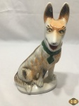 Escultura de cachorro sentado em porcelana pintada. Medindo 27,5cm de altura.