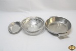 Lote composto de travessa redonda com alças, petisqueira oval e pãozeira fruteira, todas as peças em aço inox. Medindo a travessa redonda 23cm de diâmetro x 4,5cm de altura.