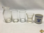Lote composto de pequeno vaso em vidro e 4 copos de aperitivo, sendo 3 em vidro e 1 em porcelana. Medindo o vaso 10,5cm de altura.