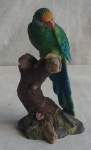 Escultura em Resina ricamente policromada representando papagaio posado em tronco de árvore. Med. Alt. 21cm