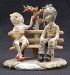 PRIMO AMORA - Escultura em resina representando "Casal no banco, com árvore". Med. ? cm.