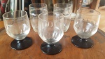 Cinco (5) copos em vidro, de diferentes modelos, sendo 3 com base no tom preto. Med. maior: 8 cm.