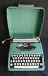 Antiga máquina de escrever portátil, marca: Olivetti - Lettera 82, no tom verde. Acondicionada em estojo original. Med.: 30 X 30 X 7 cm.