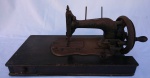COLECIONISMO - Antiga máquina de costura decorativa em ferro, apoiada sobre base de madeira. Apresenta placa de: "JOSÉ PIMENTA DE MELLO". Marcas do tempo. Med.: 14 X 11 X 10 cm.