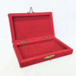 Bela caixa em madeira totalmente  revestida em veludo vermelho com detalhe costurado em fio dourado no formato de arabesco. Fecho em metal dourado. Dimensões: 5 cm x 14 cm x 23 cm.