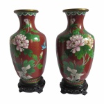 Lindo e antigo par de vasos em cobre rematado com técnica cloisonné. Decorados com peônias e pássaro sobre fundo bordô. Acompanha peanhas talhadas em madeira nobre.Exemplares de coleção e em excelente estado de conservação.Dimensões: 24 cm altura.A técnica do cloisonné é de origem bizantina e foi introduzida na China no século XIV. Sobre um objeto fabricado em metal, geralmente em cobre, aplicava-se um conjunto de finos fios dourados formando os contornos dos motivos desejados. Os favos, ou "cloisons", eram depois preenchidos com esmaltes coloridos, fortemente comprimidos e polidos até atingirem o acabamento desejado.