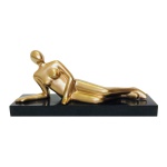 Linda escultura de mesa em metal revestido de dourado, estilo contemporâneo, representando figura feminina em posição de repouso. Base retangular em baquelite. Exemplar antigo e em perfeito estado. Dimensões: 10,5 cm x 22,5 cm x 6 cm.