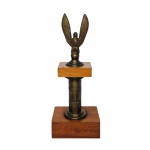 Delicada Águia em bronze  sobre base construído em madeira intercalado por haste em metal dourado.Presença de dois pequenos furos na base inferior. Dimensões: 20,5 cm x 8,5 cm x 6 cm.