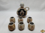 Jogo de garrafa licoreira e 6 copinhos em cerâmica pintada com relevos da Ceramart. Medindo a garrafa 16,5cm de altura.
