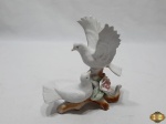 Escultura em porcelana de aves brancas sob rosa. Medindo 17,5cm de altura. Com uma perda em uma das asas.