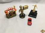 Lote composto de 4 enfeites, sendo um troféu de futebol, um tem de brinquedo, etc. Medindo o troféu 12,5cm de altura.