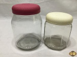 2 Potes para condimento em vidro com tampa de plástico duro. Medindo o maior 18cm de altura.