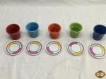Lote composto de 5 copinhos em porcelana colorida e 5 descansos de copo em melanina. Medindo os copinhos 6,5cm de altura.
