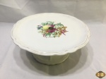Prato de bolo com pé em porcelana Saler com pintura de frutas. Medindo 29cm de diâmetro x 12,5cm de altura.