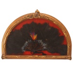 Leque de pena de avestruz acondicionado em caixa de madeira. 52 x 72 cm. A armação do leque apresenta duas partes, uma interna e outra externa e é formada de varetas, sendo que as externas têm o nome de varetas mestras, e a da frente, a principal. As varetas mestras são geralmente mais ornamentadas do que as simples, em muitas vezes apresentam as iniciais da dona do leque. No `leque indiscreto`, eram colocados pequenos espelhos que permitiam as damas ver a movimentação ao seu redor, sem serem vistas. A `folha` é a parte mais decorada do leque que podia ser feita com pinturas sobre tecido, papel, pergaminho, rendas, seda etc., sendo geralmente ornamentadas com pinturas ou bordados com lantejoulas metálicas ou mesmo com fios de ouro ou prata. É neste contexto de luxo e sedução que no século XIX toma força a `Linguagem do Leque`. Esta era um complicado sistema de posições e gesticulações que possibilitavam as damas se comunicar e flertar.