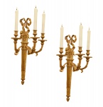 Par de arandelas para três luzes executada em bronze fundido e polido ao gosto francês. Corpo em formato oblongo apresentando decoração com laços de fita. Séc. XX. 78 x 31 x 22 cm.