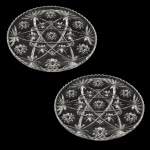 Par de pratos para bolo em cristal europeu apresentando lapidação em movimentos estrelares. Borda serrilhada. Séc. XX. 34 cm.
