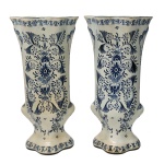 Par de vasos em faiança moldados no formato de cornetas e decorados em azul com moinhos e arranjos florais em reservas. Bases recortadas. Nos versos, marcas da manufatura de Delft. 30 x 15 x 12 cm.