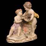 Estatueta em porcelana alemã policromada representando o futuro imperador Trajano, ainda criança, oferecendo a cabeça de um javali para a menina que se tornará conhecida como a deusa Diana, a Caçadora. No verso, marca da manufatura de Meissen. Séc. XIX. 12,5 x 12 cm. 