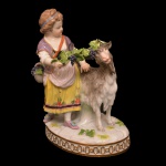 Estatueta em porcelana alemã policromada representando menina com cesto de uvas acompanhada por bode. No verso, marca da manufatura de Meissen. Séc. XIX. 12 x 11 cm.