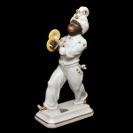 Estatueta em porcelana alemã policromada representando músico tocando pratos. Base retangular chanfrada. No verso, marca de Rosenthal, manufatura de Selb (Bavária). 