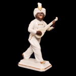Estatueta em porcelana alemã policromada representando músico tocando pequeno violão. Base retangular chanfrada. No verso, marca de Rosenthal da manufatura de Selb (Bavária). 19 x 9 cm.