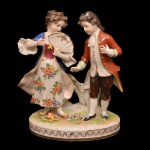 Estatueta em porcelana alemã policromada representando casal de crianças em trajes formais. Base ovalada. No verso, marca da manufatura de Volkstedt-Rudolstadt. 14 x 11 cm.