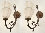 Par de arandelas para uma luz em bronze fundido e patinado. Fuste em sinuoso movimento ornamentado por predominância de elementos vegetais. Cúpula em vidro acetinado fosco e ornado por gomados em relevo com representações florais envoltas em perolados. Borda trabalhada em ondulados. 53 x 38 cm.
