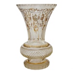Vaso em cristal com gargalo moldado em corneta, ornado por adornos florais e volutas douradas. Base com largo segmento anelado apoiado em pé circular. 26 cm. 16 cm (bocal).