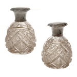 BACCARAT - Par de frascos para perfume de cristal piriformes, lapidados com adornos geométricos e encimados por tampas em prata. Contrastes da prata de Birmingham de 1933 e marcas de prateiro desgastadas. 11 cm.