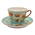 VISCONDI DE GUAY - Xícara com pires de porcelana francesa. Apresenta decoração em ambas as peças predominantemente em verde berilo, decorado com flores douradas em relevo. Na xícara ao centro, coroa de conde dourada e também em relevo. No pires a marca deposé. Pasta dura. França. Séc. XIX. 5.5 x 10 cm (xícara). 14 cm (pires)