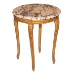 Mesa lateral em madeira dourada, ornamentada por frisos e folhagens em relevo. Tampo circular em mármore rajado, apoiada em saia realçada por bordas geométricas. Pernas recurvas rematadas por pequenos pés retos. 74 x 56 cm. 