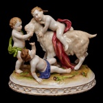 Estatueta em porcelana alemã policromada representando grupo de três crianças brincando com bode. No verso, marca da manufatura de Plaue-Saxe de C.G. Schierholz & Filho. 16 x 18 cm.