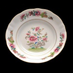 Covilhete de porcelana apresentando fundo branco com guirlandas florais predominando a cor rosa. No fundo as inscrições: NG Portugal (Aveiro), comemoração Companhia das Índias, Família Rosa. 12,5 cm.