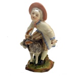 Estatueta de porcelana alemã, representando menino com bode. Marca da manufatura no fundo. Séc. XX. 13 cm. 