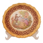 Prato de porcelana francesa Limoges com representação de cena galante ao centro, borda apresentando decoração recortada em ouro e vermelha. No fundo as inscrições: Manufatura Jammet-Seignolles, Limoges, France. Exclusive Rechaussé Main. 22 cm.