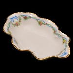 Covilhete oval de porcelana francesa. Fundo de superfície branca com guirlanda floral. Borda recortada. No fundo as inscrições: Limoges – France. Séc. XX.  4 x 17 cm.