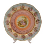 Medalhão de porcelana azul e dourado, decorado em policromia no centro e na borda, com figuras de casais em cena galante. 33,5 cm.