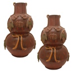 Par de grandes vasos de cerâmica na cor bordo. Apresenta forma de duplo bulbo com decoração em relevos com folhagens nos tons de verde e amarelo. 