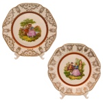 Par de medalhões sextavados em porcelana europeia, com bordas hexagonais decoradas com adornos dourado. Centros ornamentados por cenas românticas policromadas. Assinados nos versos A. Branca. 32 cm.