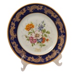Prato em porcelana francesa com belíssima decoração na borda em ouro e azul cobalto, com arranjos florais ao centro sobre fundo branco. Etiqueta na frente `Limoges France`. No fundo as inscrições: Porcelaine Ternet, Limoges. France. Rechaussé Main. 5,5, cm.