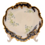 Prato em porcelana francesa. Borda recortado e ondulado com azul cobalto com ouro com delicados arranjos florais sobre fundo branco. No fundo as inscrições: M. Rodet, Limoges, France. 23,5 cm.