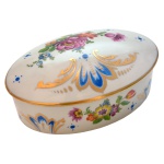 Caixa para joias em porcelana francesa. Formato oval com decoração floral e ouro. No fundo as inscrições: Limoges – France. 7 x 15 x 10 cm.