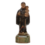 Santo Antônio - Imagem brasileira em madeira policromada representando Santo Antônio em suas tradicionais vestes, com o Menino Deus recolhido ao braço esquerdo. Peanha facetada e chanfrada. Séc. XIX. 12.5 cm. 