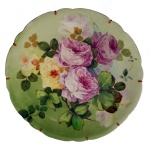 Medalhão em porcelana francesa apresentando superfície na cor verde, com decoração com grande flores e folhas. Borda ondulada. No verso marcas J.P.L. France. 35 cm.