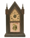 Relógio de parede, popularmente conhecido como capelinha. Maquinário da manufatura norte americana de `Waterbury Clock Co.`. Caixa em madeira com aplicação de porta em vidro decorado com pássaro e flores. Mostrador em flandres com algarismos romanos. Necessita de manutenção e restauro. EUA. C. de 1920. 49 x 26 x 11 cm.