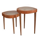Conjunto de duas mesas de madeira em sucupira, e formato oval irregular que se encaixam parcialmente. Tampo de vidro levemente fumê. 99 x 70,5 x 65 cm / 79 x 70,5 x 62 cm.