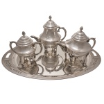 Serviço para chá de metal espessurado a prata. Bules de forma circulares e pés altos. Constando de bandeja de forma oval (55 x 32 cm), bule (20 cm), leiteira (18 cm) e açucareiro (15 cm).