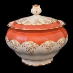 Bowl com tampa em porcelana alemã, de formato bojudo, decorado com larga faixa em tons de rouge de fer, realçada por adornos dourados estilizados. Tampa abobadada no estilo e pega em botão floral. No verso, marca da manufatura de Furstenberg. Séc. XIX-XX. 18 x 19 cm / bocal com 17 cm.
